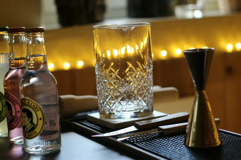 Barwerkzeug mit Rührglas, Jigger und Tonic-Flaschen auf der Bar