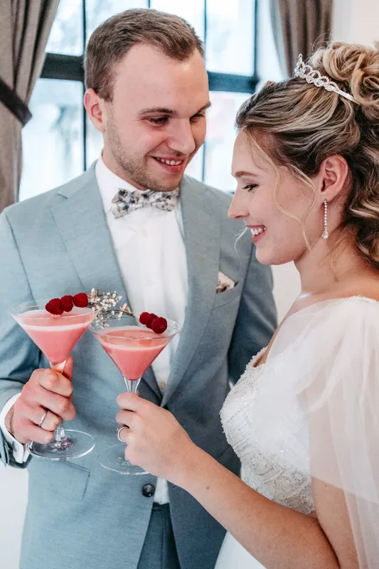 Brautpaar mit rosafarbenen Cocktails, garniert mit Himbeeren