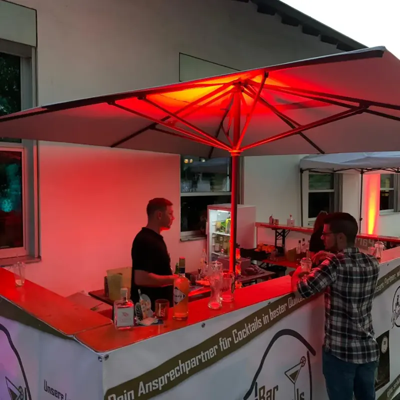 Mobile Cocktailbar unter einem rot beleuchteten Schirm