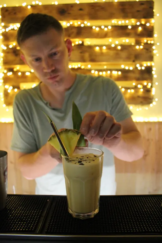 Michael garniert einen Cocktail mit einem Ananasblatt