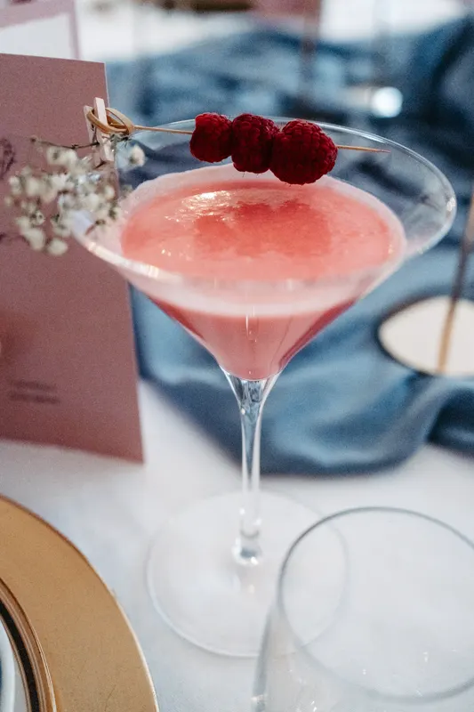 Rosafarbener Cocktail mit Himbeeren auf einem Hochzeitstisch