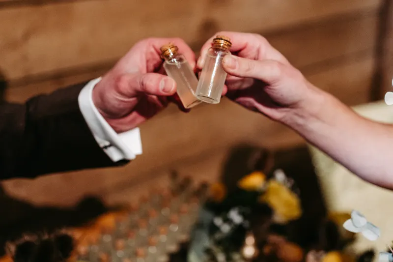 Zwei Gäste stoßen mit kleinen Shot-Fläschchen an